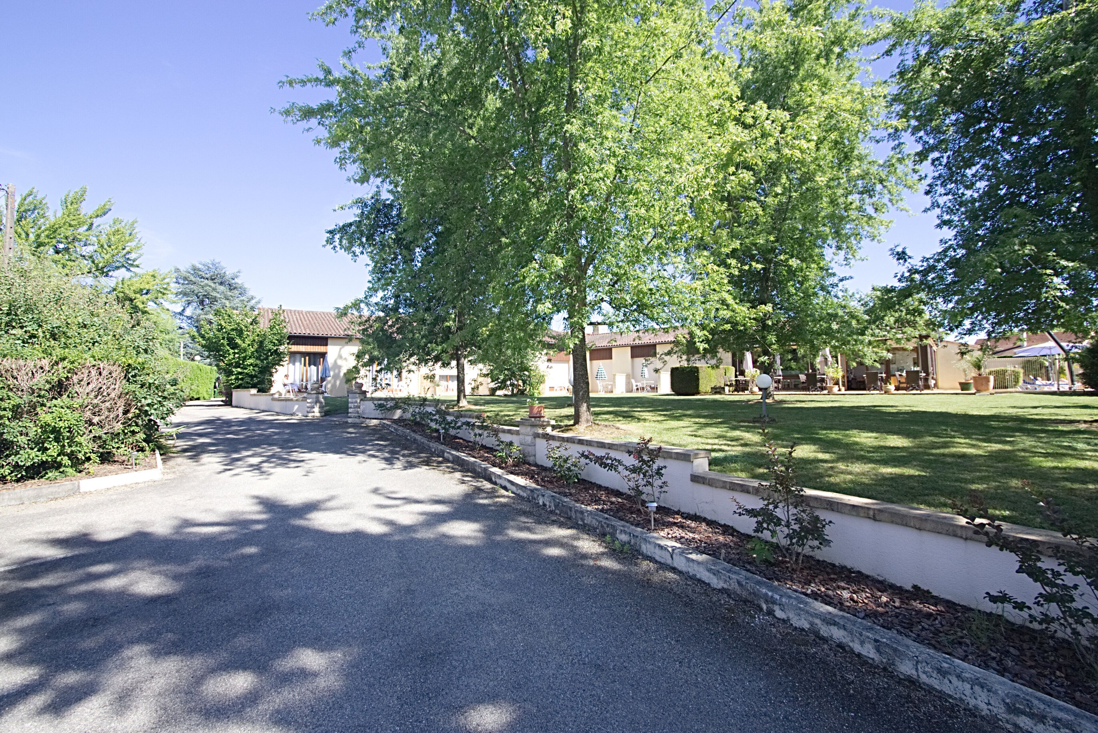 A residential street with houses, a well-maintained lawn, and a clear sky.