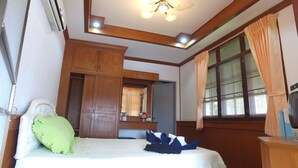 Un dormitorio con cama, armario de madera, espejo y ventana con cortinas.