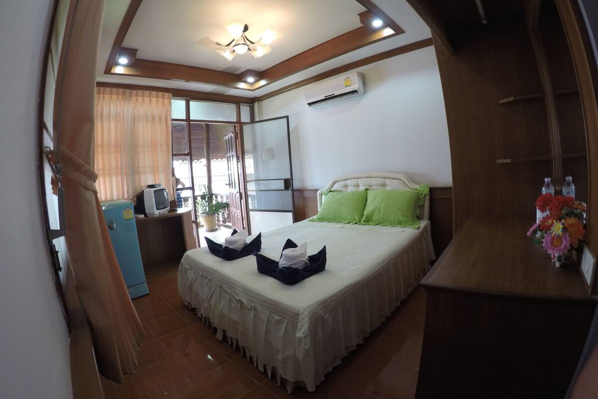 Ein Schlafzimmer mit einem Bett, einem Fernseher, einem Heizkörper und einem Fenster mit Vorhängen.