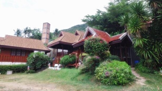 Una casa tradicional con tejado de baldosas, rodeada de abundante vegetación y un camino que lleva a ella.