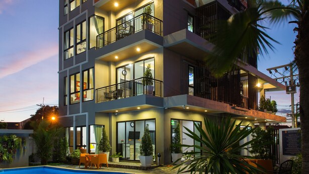 Un hôtel à plusieurs étages doté d’une piscine, d’un espace extérieur aménagé et de balcons.