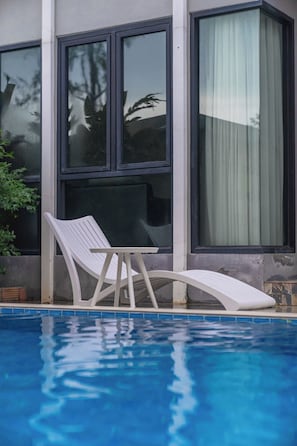 A pool with a white lounge chair and a window with a curtain. - The Lucky Beach Ao Nang (Krabi)
