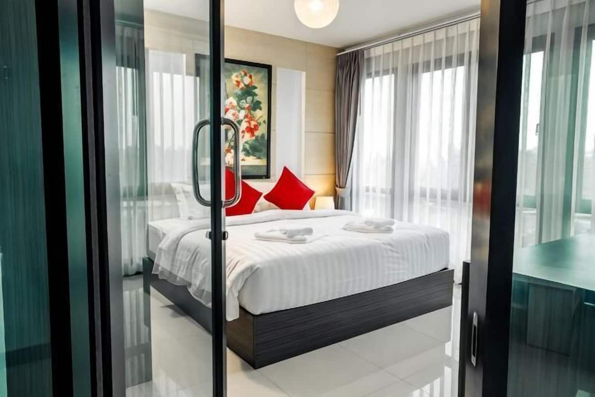 Une chambre d’hôtel moderne avec un grand lit, une porte vitrée et une vue sur la ville.