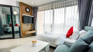 Une chambre d’hôtel moderne équipée d’un lit, d’un canapé, d’une télévision, d’un bureau et d’une fenêtre avec des rideaux.