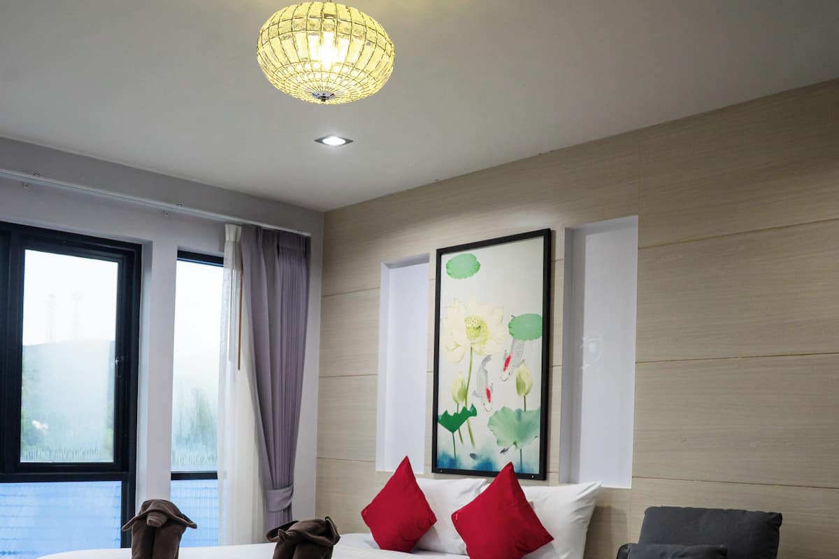 Une chambre moderne avec un grand lit, un canapé, un tableau et un luminaire au plafond.