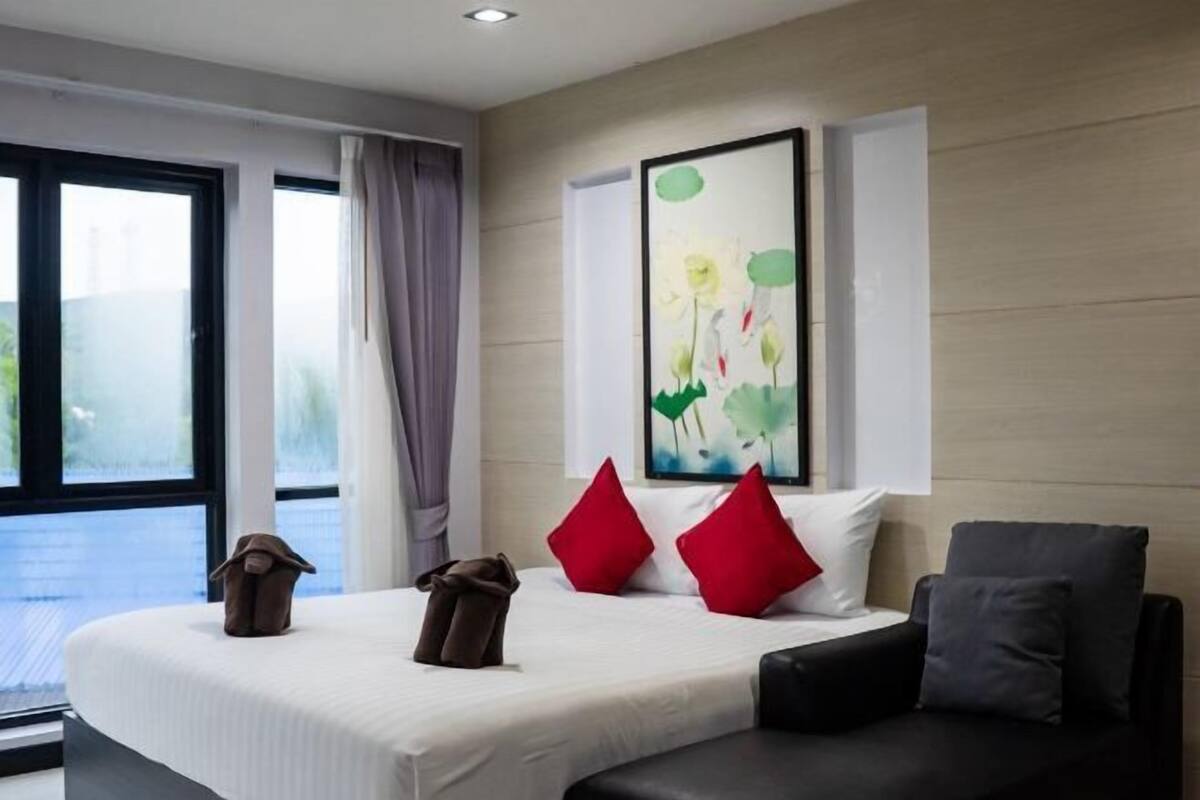 Une chambre d’hôtel moderne avec un grand lit, un canapé, un tableau au mur et une vue par la fen être.