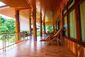 A wooden deck with lounge chairs and a railing, overlooking a lush green landscape. - Bor Hin Resort (Ko Pha-ngan)