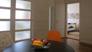 Un comedor con una mesa redonda, un cuenco de fruta y una silla naranja.