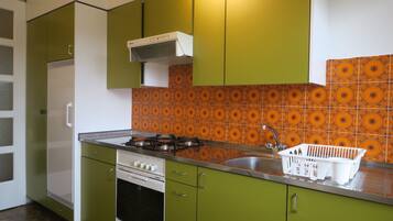A kitchen with green cabinets, a gas stove, a white oven, and a patterned backsplash.