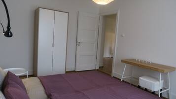 A bedroom with a bed, a desk, a wardrobe, and a hanging lamp.