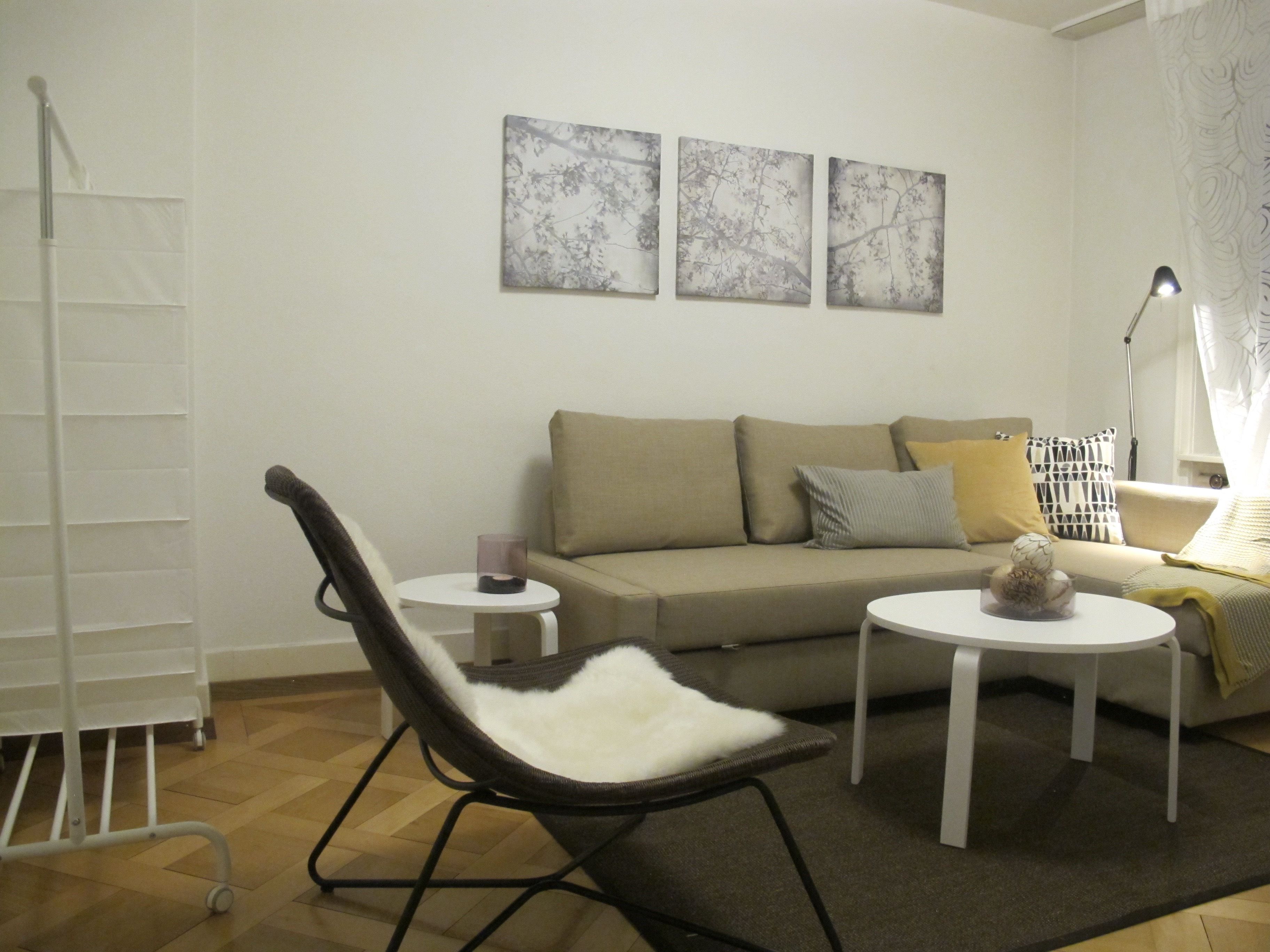 A living room with a sofa, two side tables, a chair, and wall art.