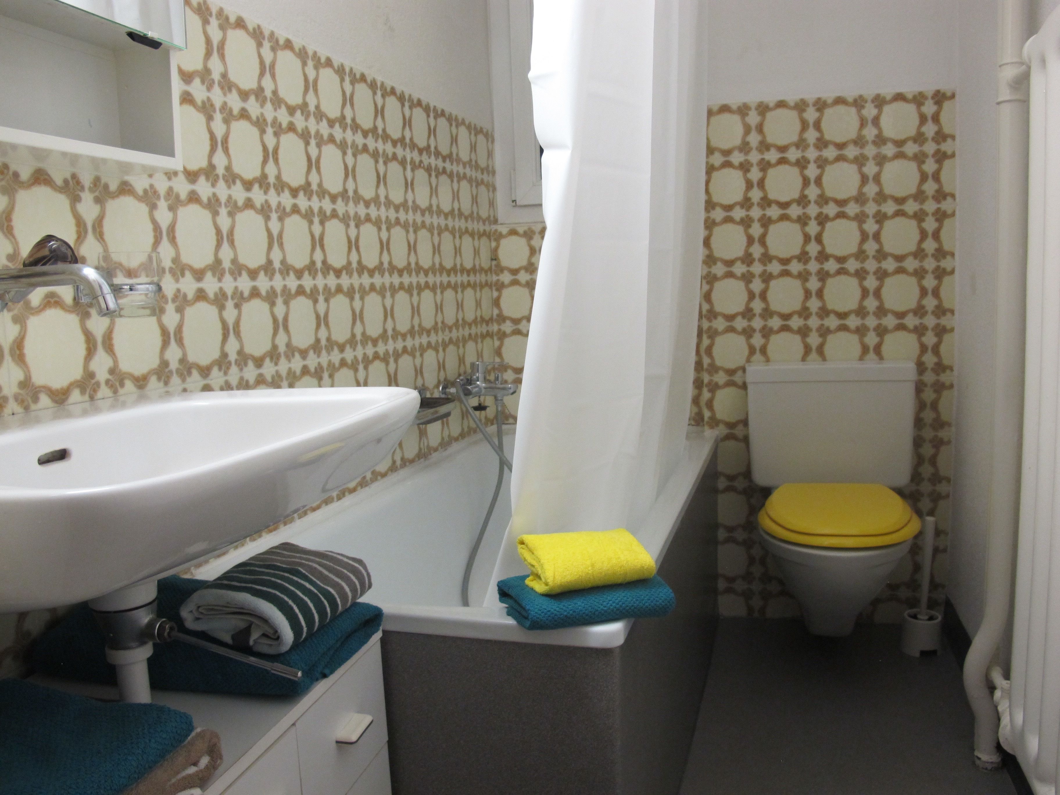 Une salle de bain avec un lavabo, une baignoire, des toilettes et des murs à motifs.