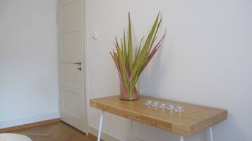 Une pièce avec une table en bois, un vase contenant des feuilles vertes et roses, et une porte blanche.