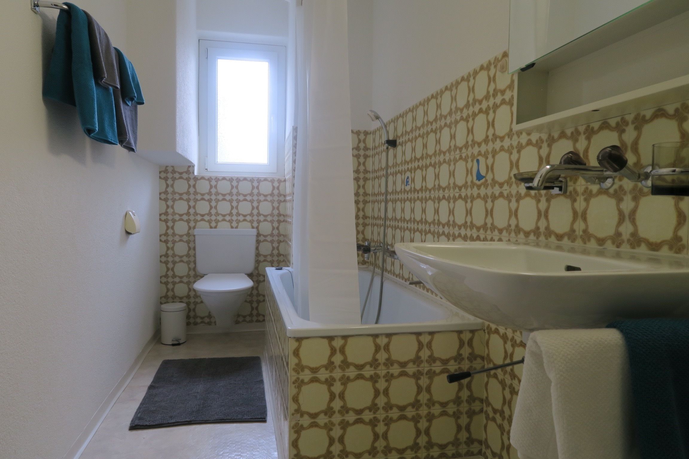 A bathroom with a toilet, bathtub, sink, and patterned walls.