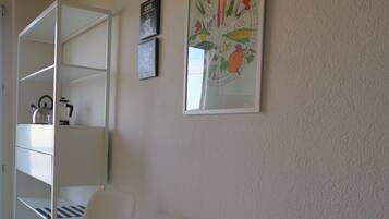 Een kamer met een witte tafel, twee witte stoelen, een klok en een lijst met een afbeelding aan de muur.