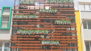 A multi-story building with a modern design, featuring horizontal wooden slats and green plants. - Opi Indah Hotel (Palembang)
