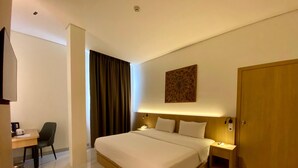 A modern hotel room with a large bed, bedside tables, a desk, and a wardrobe. - Opi Indah Hotel (Palembang)