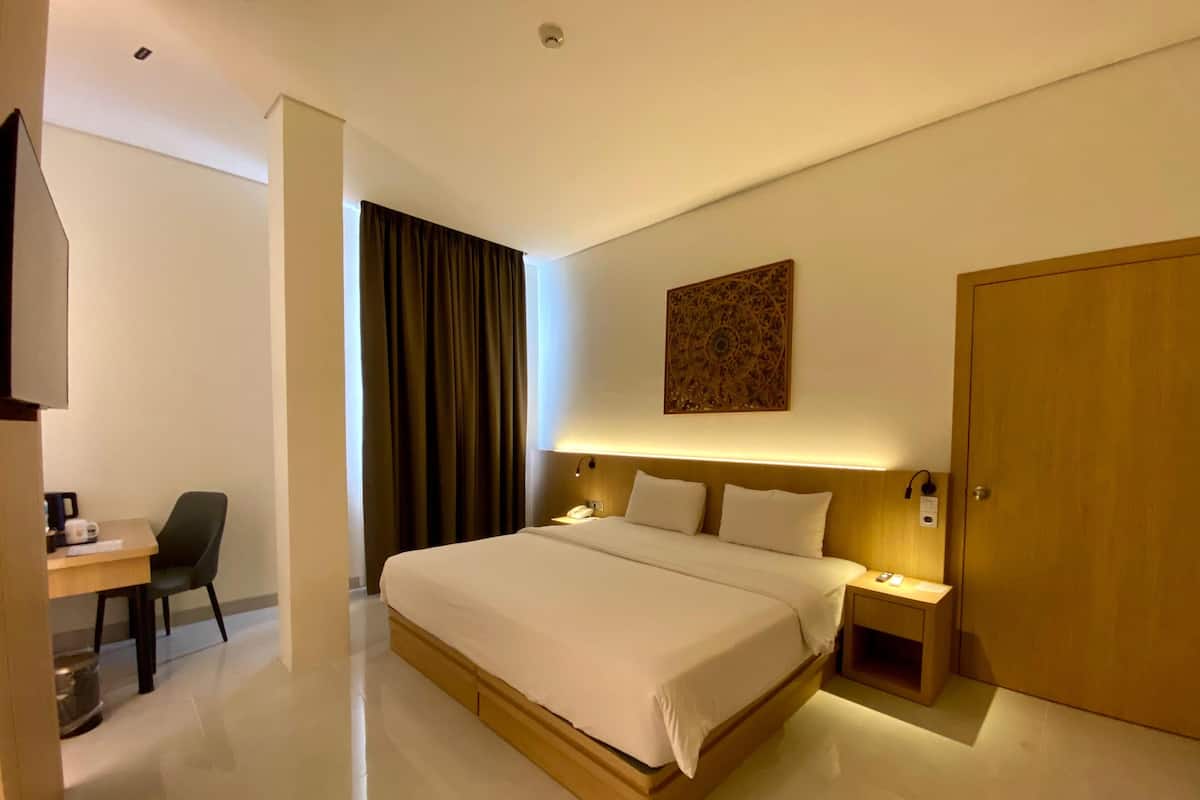 Ein modernes Hotelzimmer mit einem großen Bett, Nachttischen, einem Schreibtisch und einem Kleiderschrank.