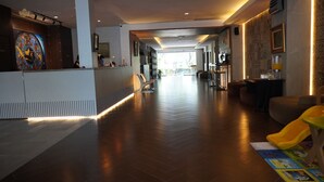A spacious hotel lobby with a reception desk, seating area, and a children's play area. - Opi Indah Hotel (Palembang)
