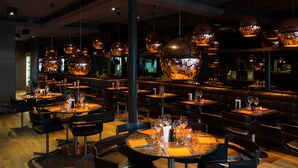 A restaurant with round tables, black chairs, and hanging spherical light fixtures. - Hotel Le Florentin (Florenville)