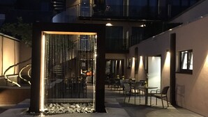 A modern building with a rooftop terrace, outdoor seating area, and a decorative water feature. - Hotel Le Florentin (Florenville)