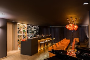 A bar area with a counter, stools, and a piano. There is a bar stocked with bottles and glasses.