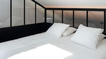 A modern bedroom with a large bed, white bedding, and a black headboard.