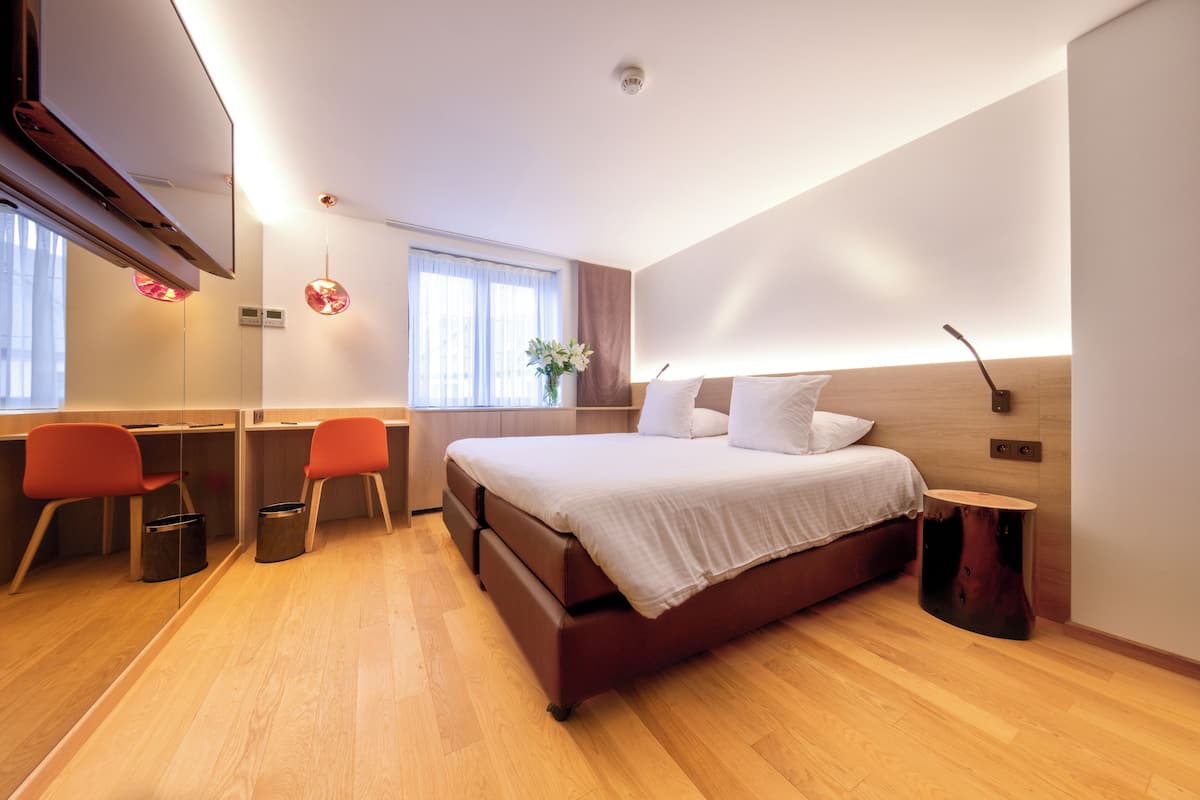 A modern bedroom with a large bed, a desk, two chairs, and a small table.