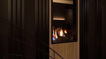 A modern interior with a fireplace, a wooden wall, and a metal staircase.