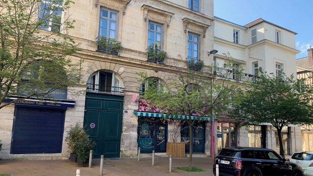 A multi-story building with a green door, a restaurant sign, and a parked car. - Chambres Les Carmes (Rouen)