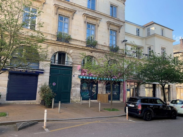 Un edificio de varios pisos con una puerta verde, un letrero de restaurante y un coche estacionado.