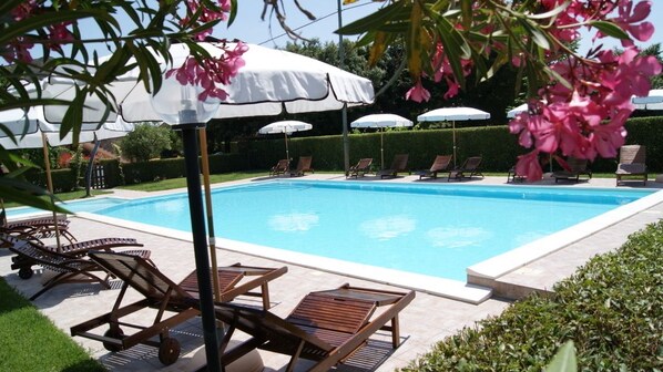 Una piscina con sillas de descanso y sombrillas.