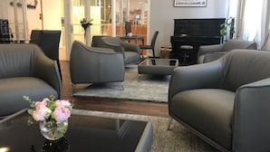 A modern living room with grey leather sofas, a glass coffee table with a vase of flowers, and a black TV stand. - Hotel Bel'Espérance (Geneva)