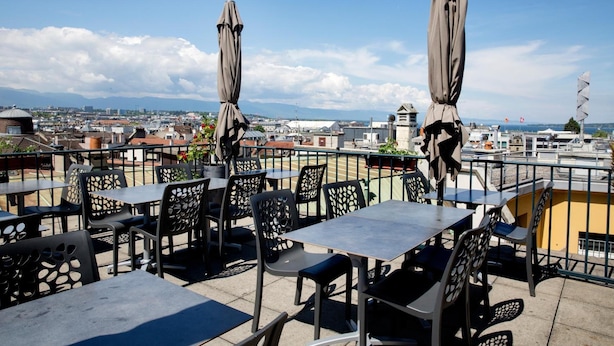 A rooftop terrace with tables and chairs, umbrellas, and a view of the cityscape. - Hotel Bel'Espérance (Geneva)
