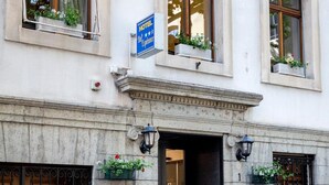 A hotel entrance with a black door, a stone facade, and flower boxes on the windowsills. - Hotel Bel'Espérance (Geneva)