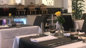 A restaurant interior with tables set for dining, a clock on the wall, and a plant in the corner. - Hotel Bel'Espérance (Geneva)