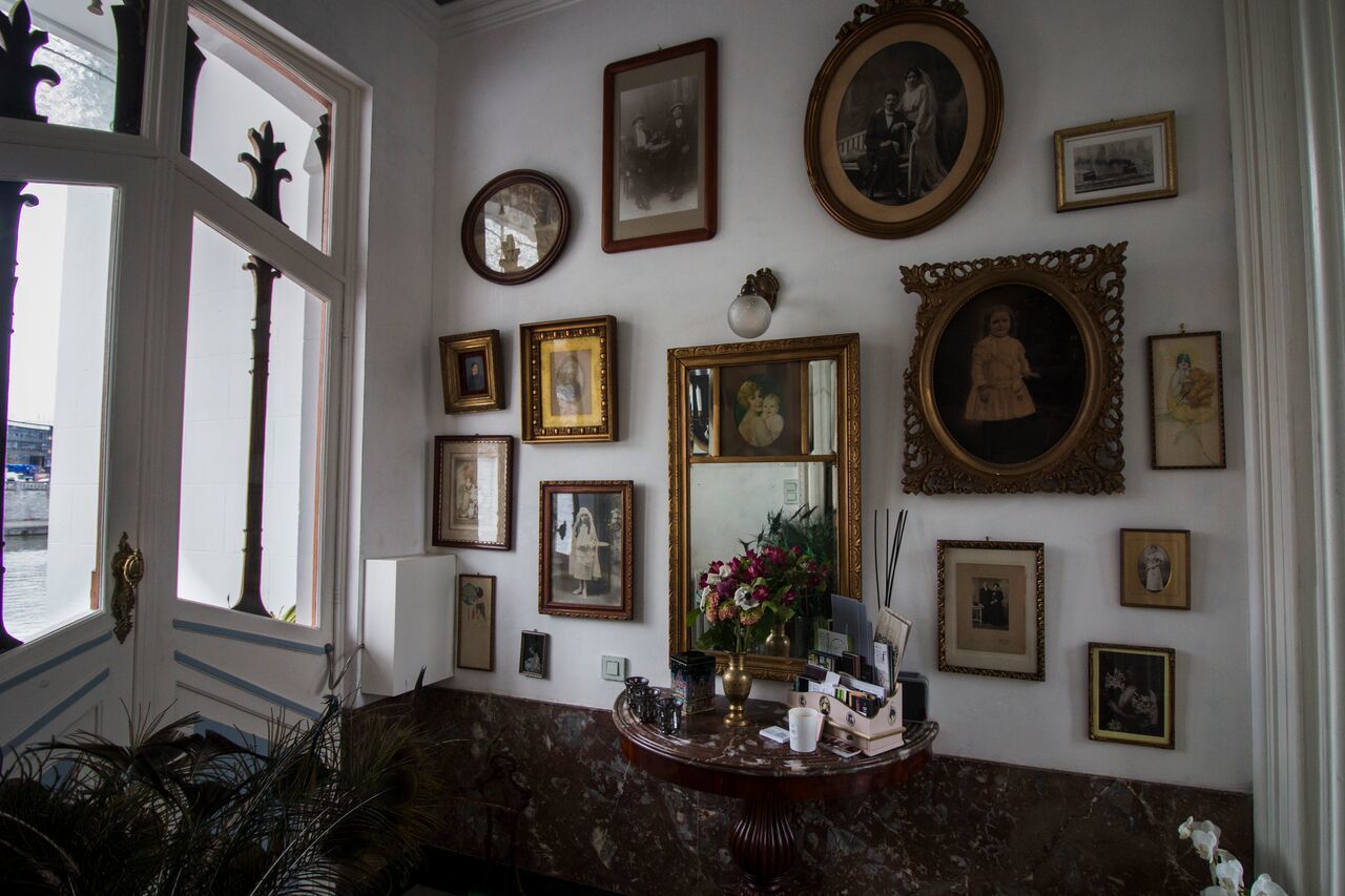 Una habitación con suelo de mármol, un espejo grande y varias fotografías enmarcadas en la pared.