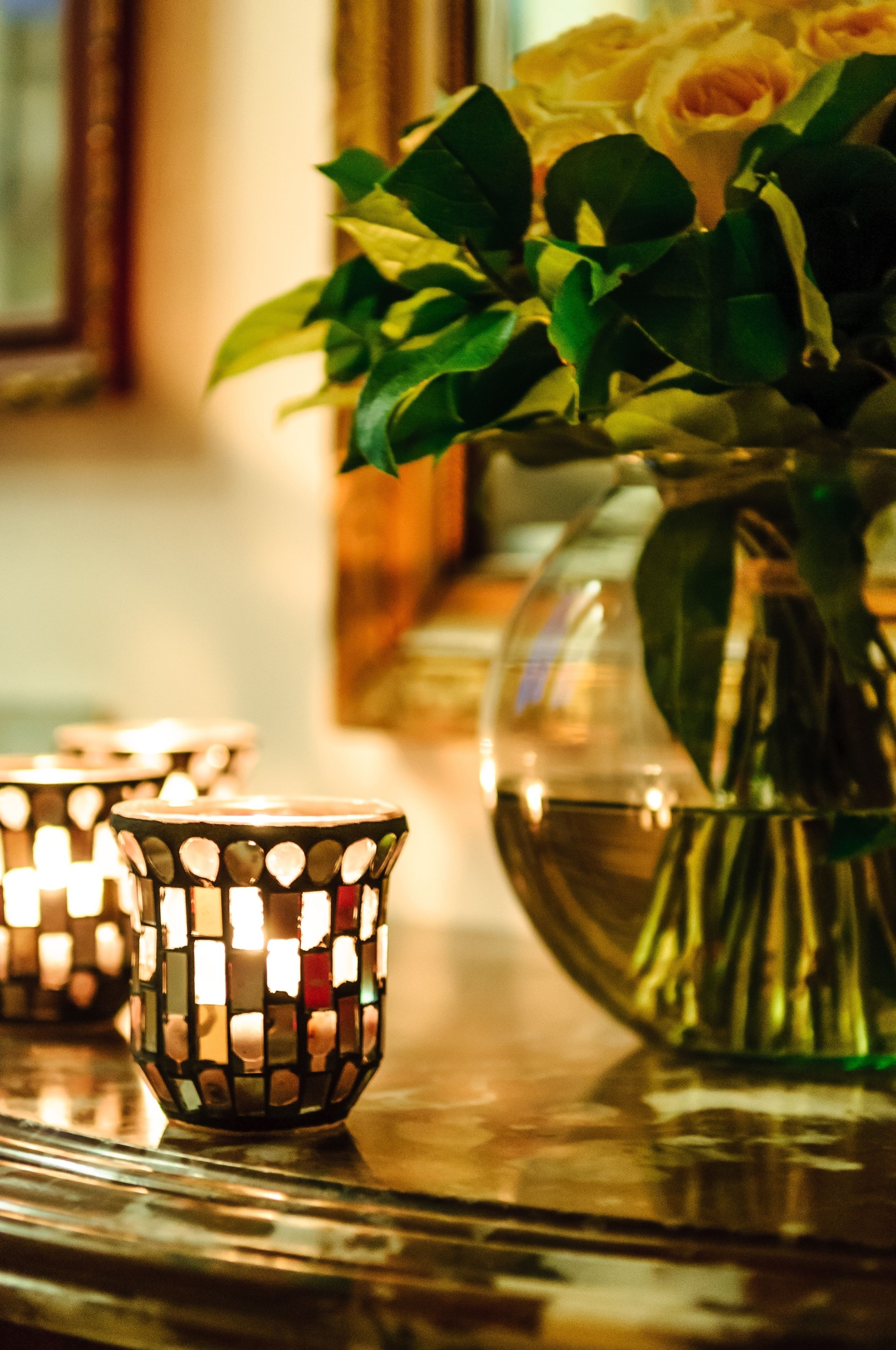 Ein Tisch mit Blumen in einer Vase und brennenden Kerzen.