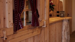 A wooden interior with a window featuring patterned curtains, a wooden counter, and a vase with flowers. - Dalla Natura la Salute (Giustino)