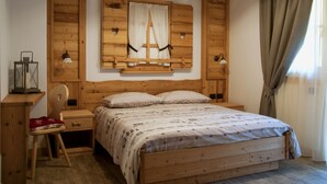 A wooden-framed bedroom with a bed, a chair, a nightstand, and a wall-mounted shelf. - Dalla Natura la Salute (Giustino)