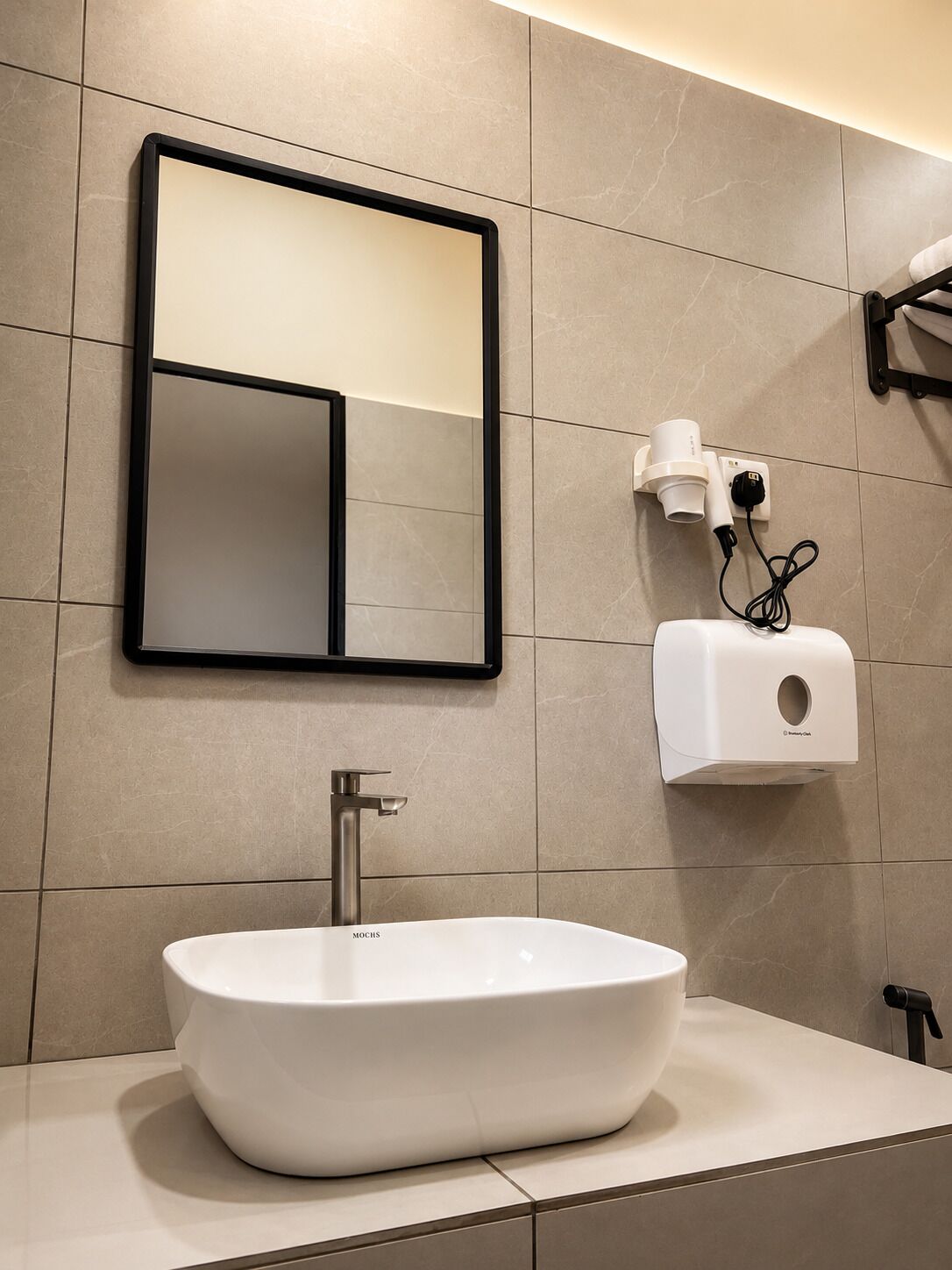 A modern bathroom with a large mirror, a vessel sink, and a hand dryer.
