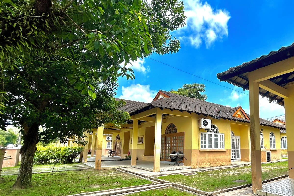 A yellow building with a tiled roof, a covered patio area, and a large window.