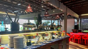 A buffet setup with various dishes and utensils, a blue and white patterned countertop, and red chairs in the background. - RUMBIA RESORT VILLA Paka Terengganu  (Dungun)
