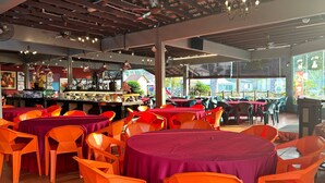 A restaurant with multiple tables and chairs, a bar area, and large windows offering a view of the outside.