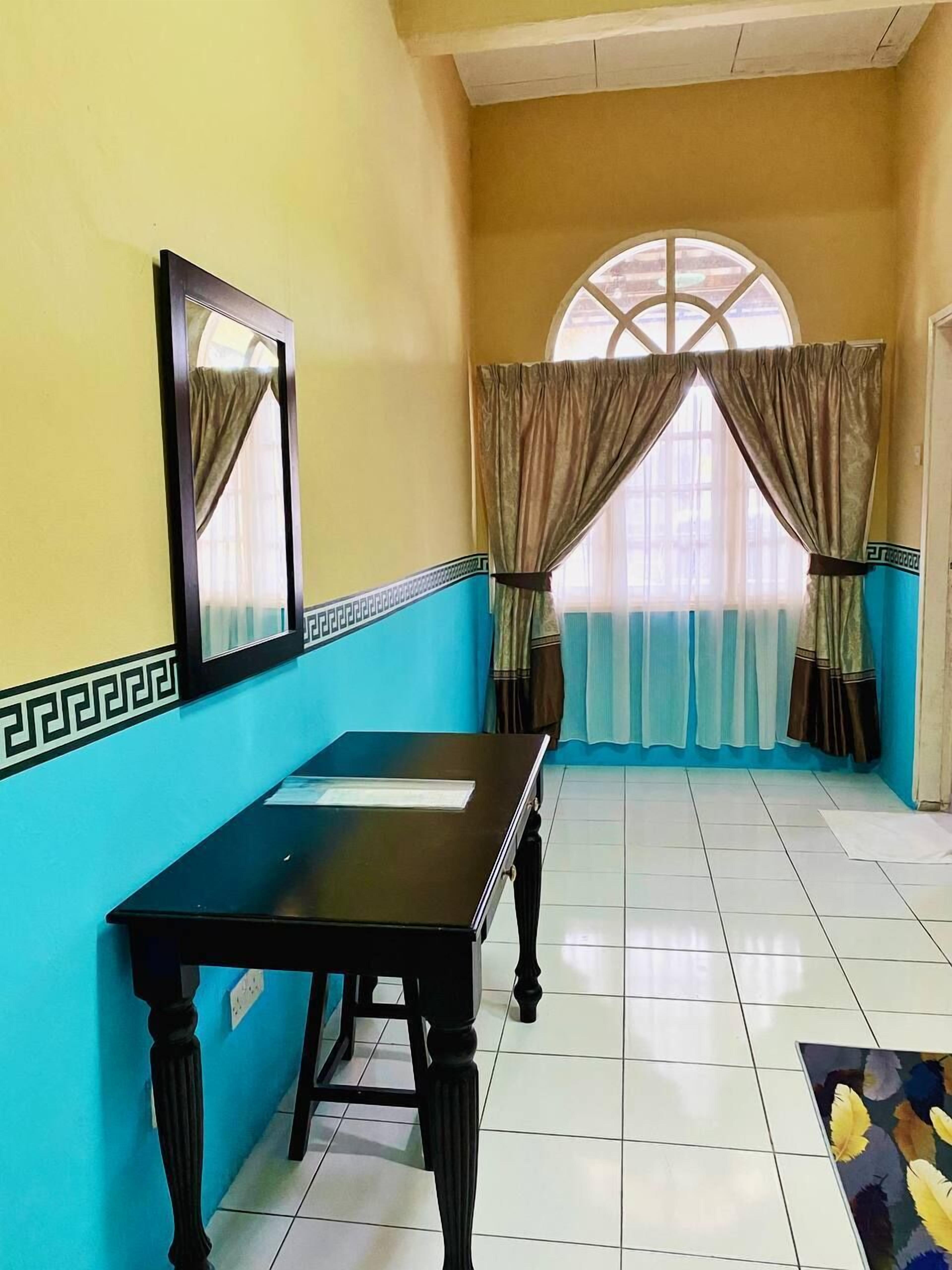 Una habitación con un ventanal, una mesa y cortinas.
