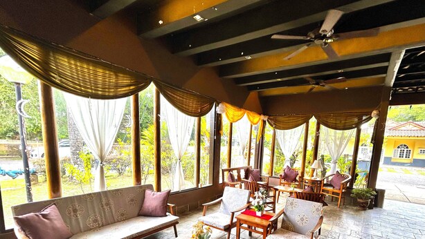 A spacious indoor seating area with a wooden coffee table, cushioned seating, and large windows offering a view of the outdoors. - RUMBIA RESORT VILLA Paka Terengganu  (Dungun)