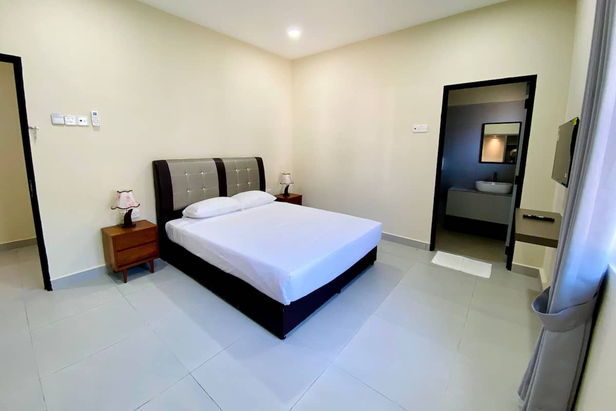 A modern bedroom with a large bed, bedside tables, a mirror, and a bathroom visible through an open door.