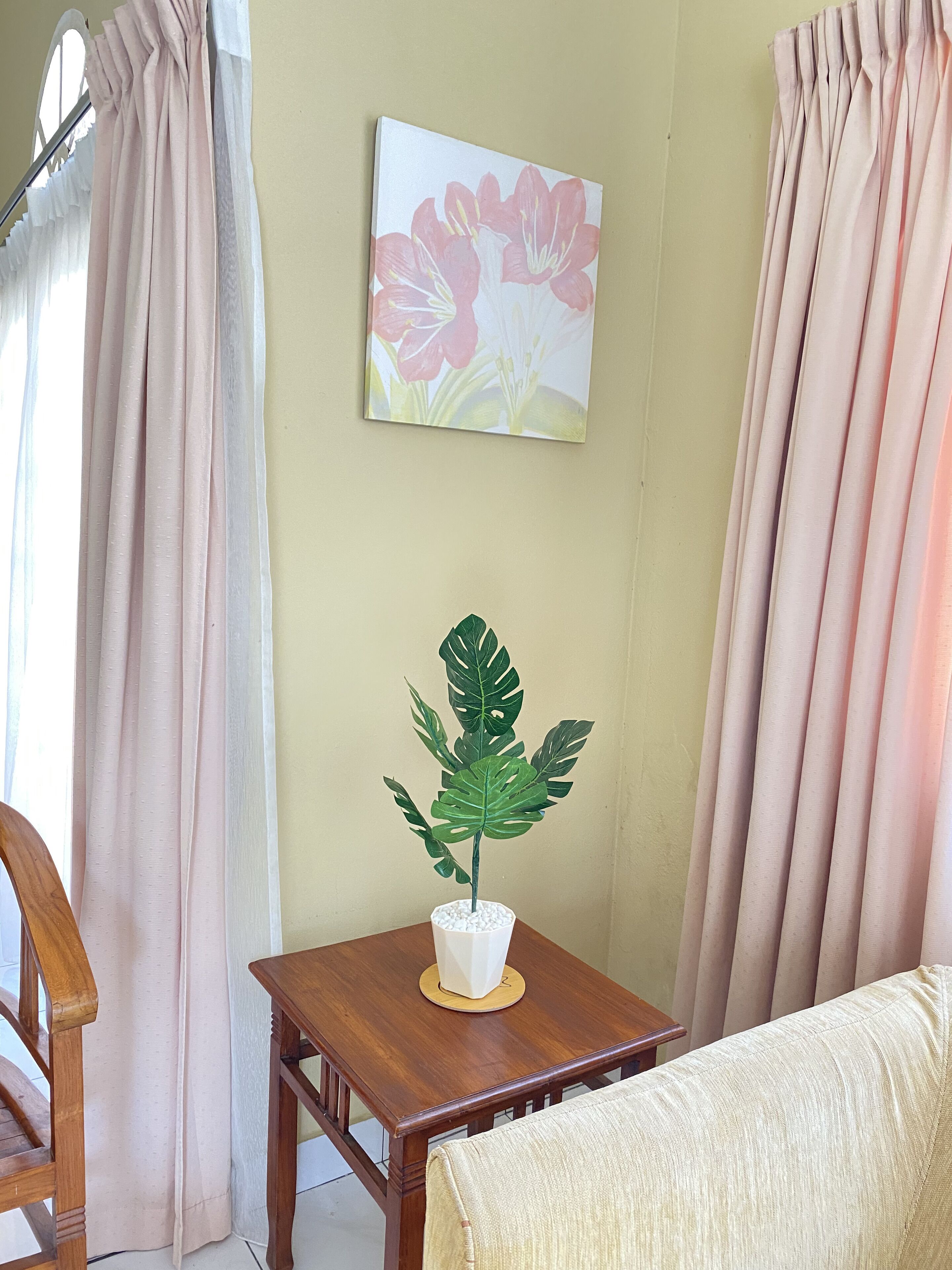 Een kamer met een houten tafel, een potplant, een bank en gordijnen.