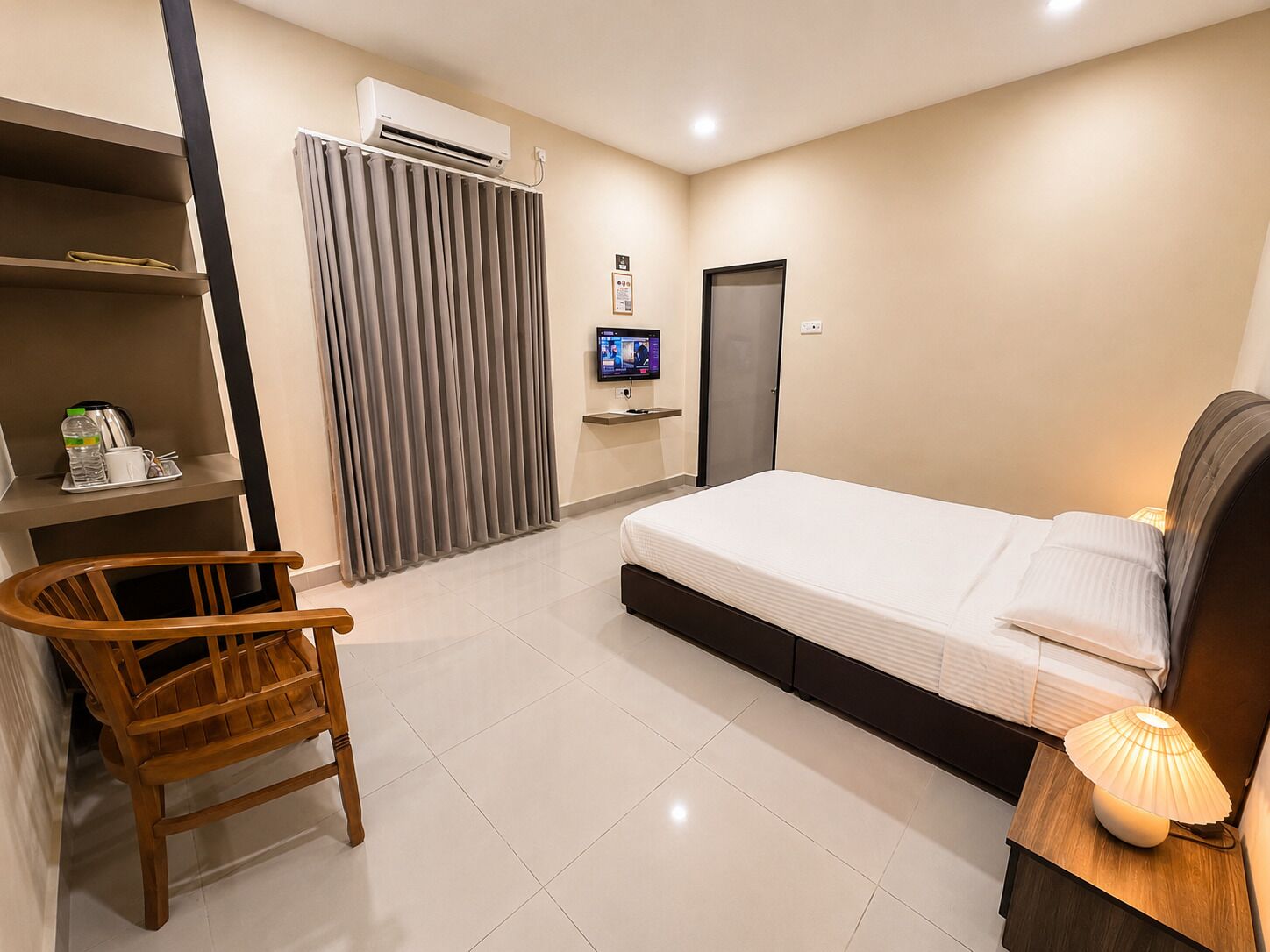 Habitación de hotel con cama, televisión, escritorio con silla, armario y aire acondicionado.