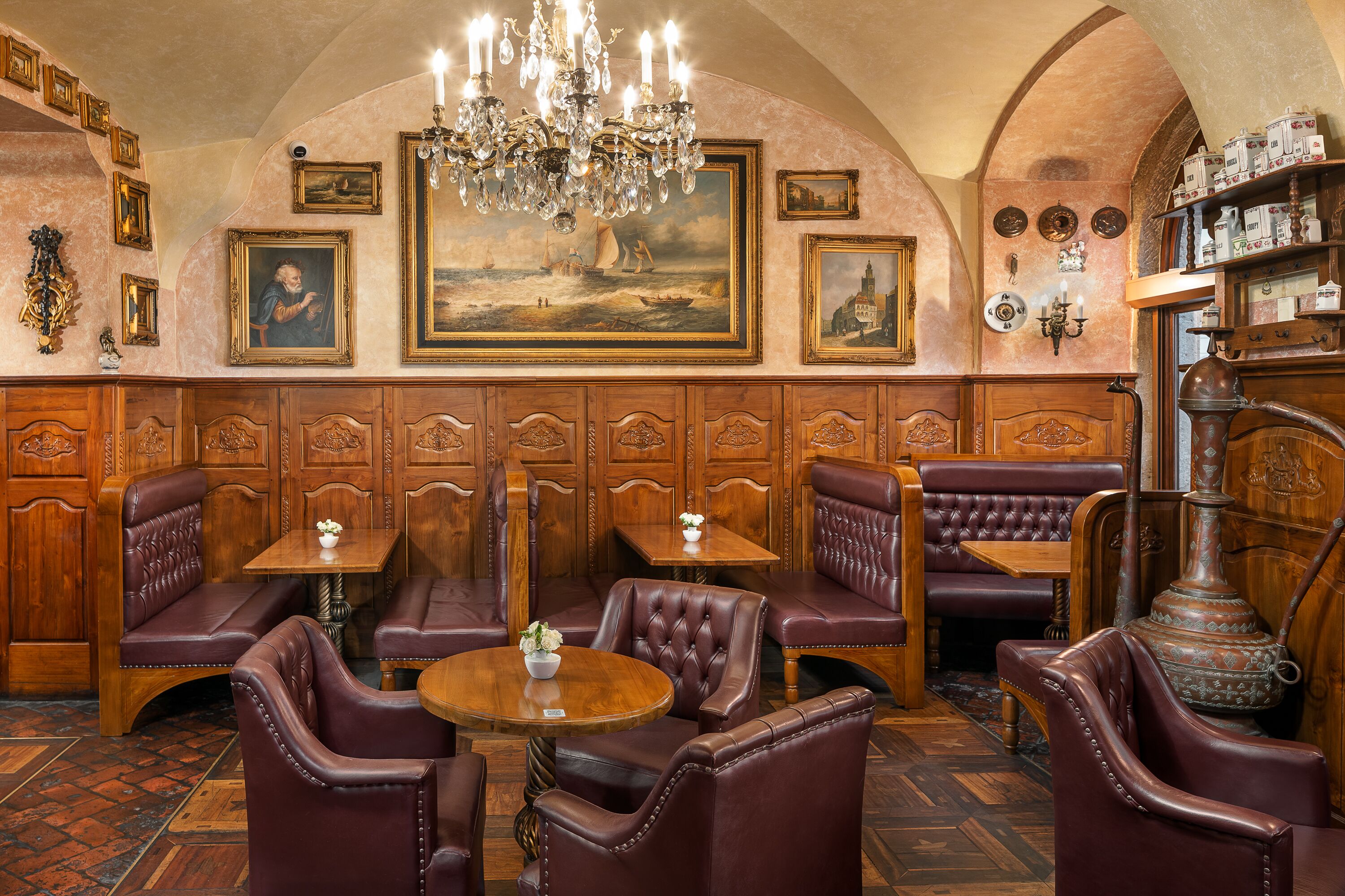 A vintage-style restaurant with wooden paneling, leather booths, and a chandelier.